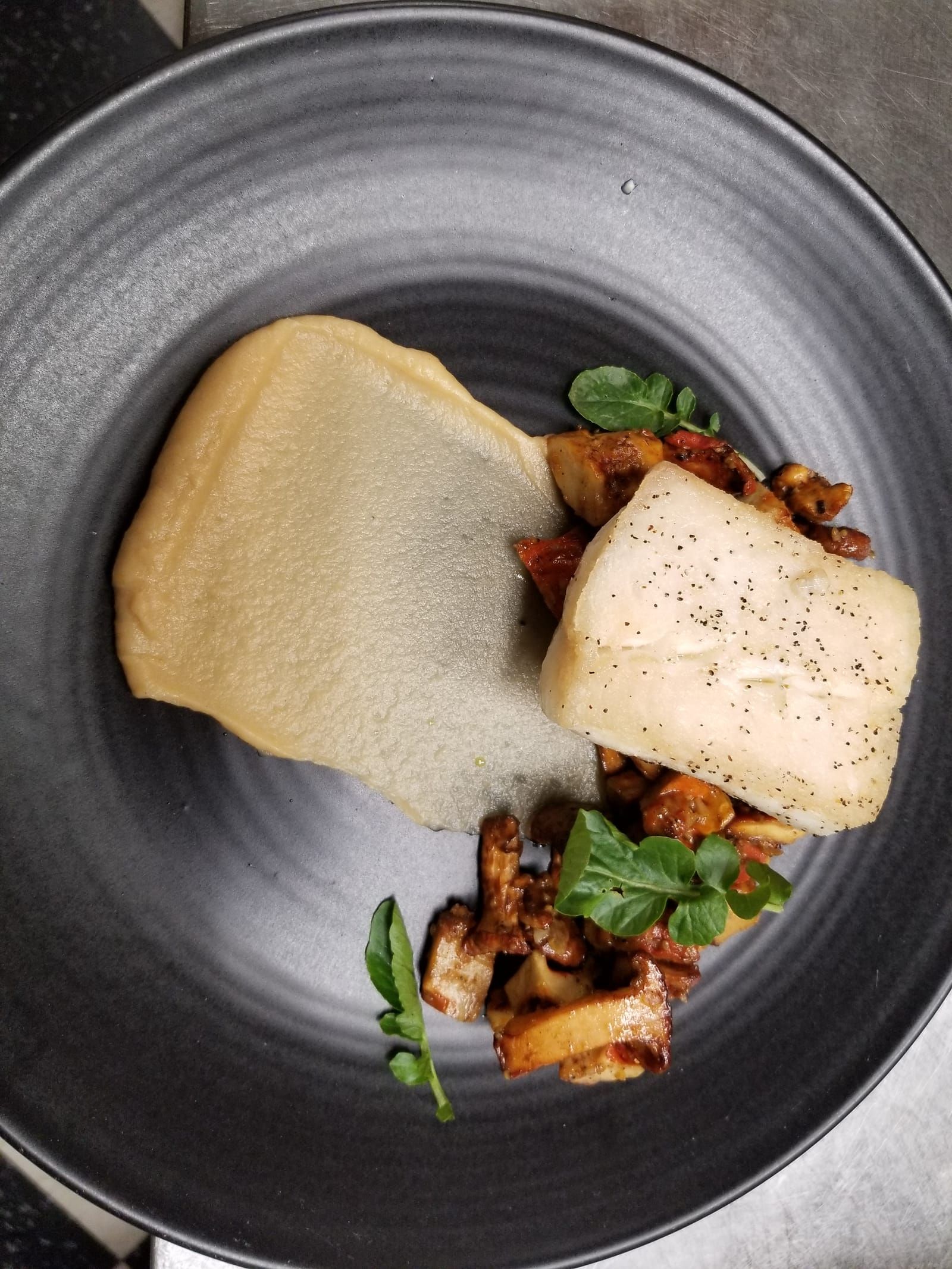 Halibut on a dark plate with chanterelles